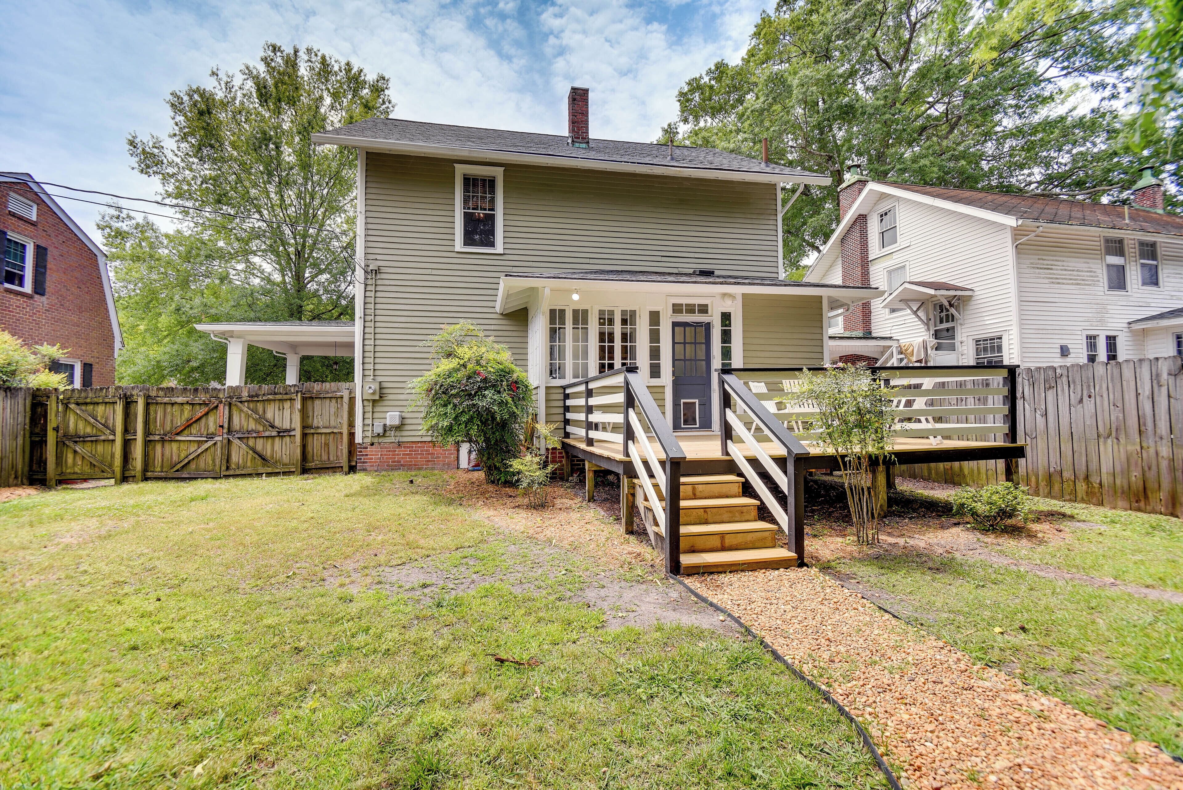 A two-story house with a covered porch, a wooden staircase, and a fenced backyard.