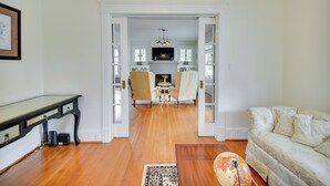 A living room with a sofa, a coffee table, and a TV in the background. There is a door leading to another room. - Elizabeth City Vacation Rental: Gazebo w/ Hot Tub! (Elizabeth City)