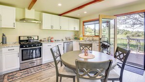 A kitchen with white cabinets, a stove, and a dining area with chairs and a table. - Julian Cottage Stay w/ Near Wildlife & Wineries (Julian)