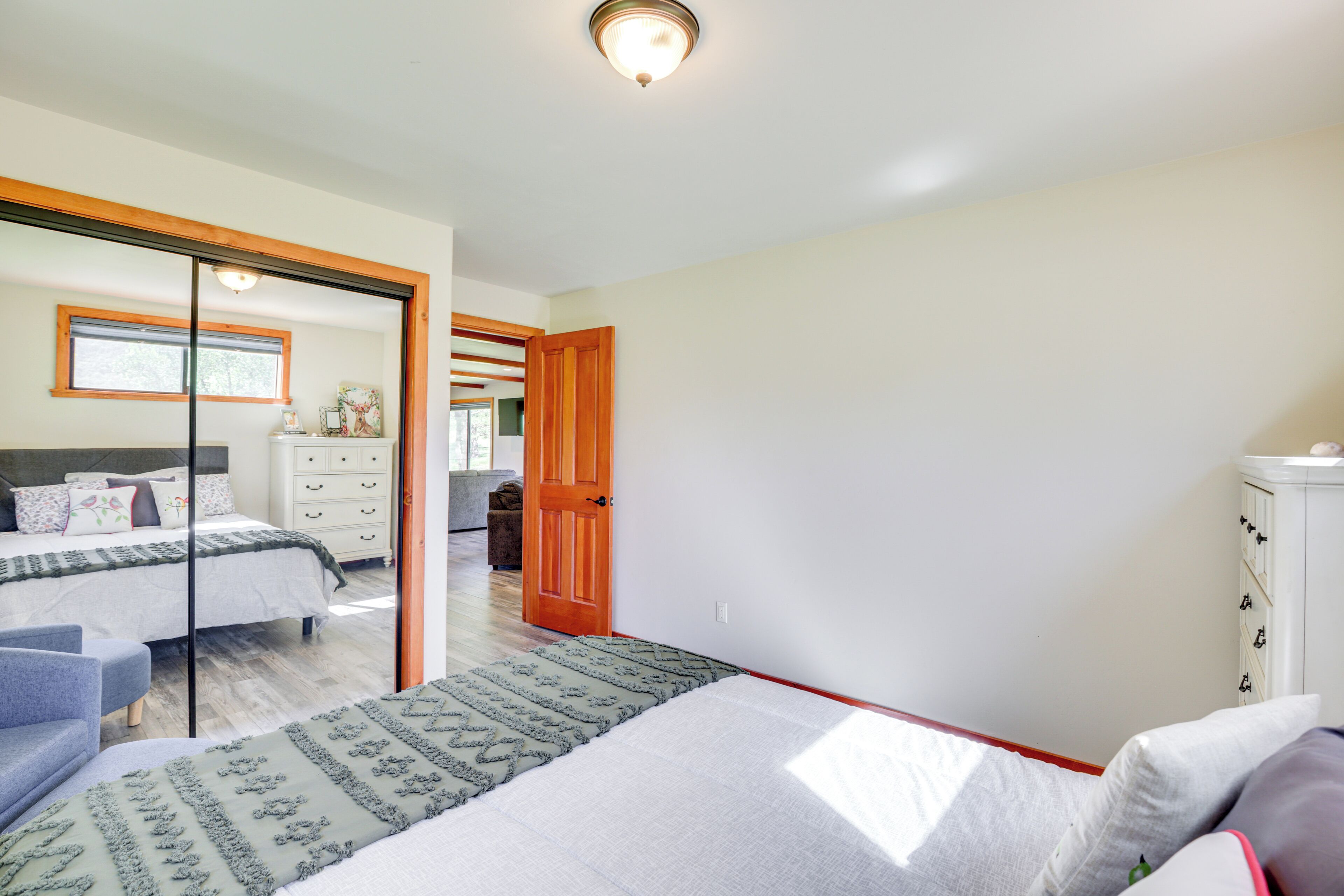 A bedroom with a large bed, a dresser, and a mirror.