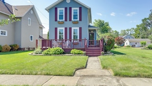 A two-story house with a front porch, a small garden, and a clear sky. - Vermilion Home - Walk to Main Street Beach! (Vermilion)