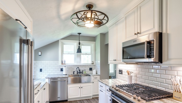 A modern kitchen with white cabinets, stainless steel appliances, a built-in microwave, and a wood floor. - Vermilion Home - Walk to Main Street Beach! (Vermilion)