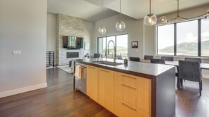 A modern kitchen with a large island, wooden cabinets, and a stone accent wall.
