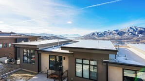 A modern building with large windows and a flat roof, overlooking a mountainous landscape.
