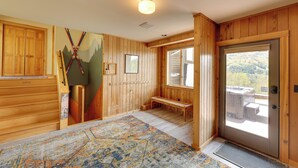 A wooden interior with a bench, a door leading outside, and a mountain mural on the wall.