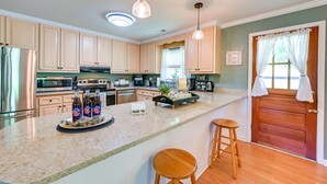 A kitchen with wooden cabinets, stainless steel appliances, a granite countertop, and a wooden door with a window. - 'the Travis House at Lantern Springs' on Farm! (Lexington)