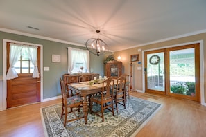 A dining room with a wooden table and chairs, a chandelier, and a view through a glass door. - 'the Travis House at Lantern Springs' on Farm! (Lexington)