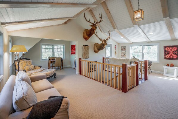A spacious living room with a high ceiling, a wooden staircase, and two mounted deer heads. - Tranquil Wyoming Cabin Near Uintas - 105 Acres! (Evanston)