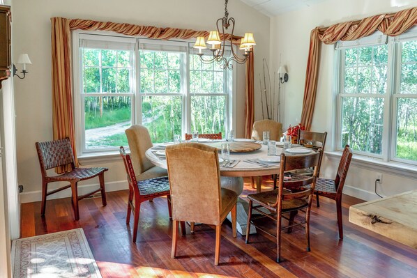 A dining area with a round table, six chairs, and a chandelier. - Tranquil Wyoming Cabin Near Uintas - 105 Acres! (Evanston)