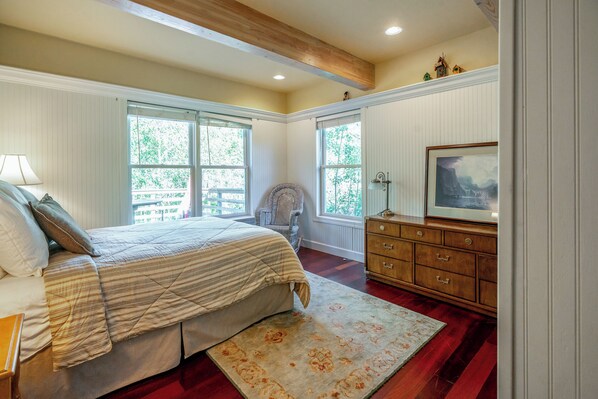 A bedroom with a bed, dresser, chair, and windows.