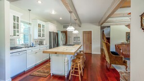 A spacious kitchen with white cabinetry, a central island with stools, and a wooden ceiling. - Tranquil Wyoming Cabin Near Uintas - 105 Acres! (Evanston)