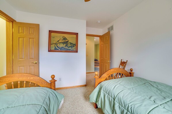 A bedroom with two wooden beds, a painting on the wall, and a door leading to another room. - Waterfront Lake Huron Getaway w/ Private Beach! (Rogers City)