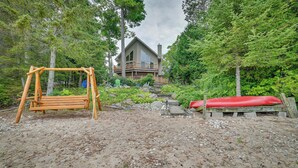 Une cabane dotée d’une terrasse et d’une balançoire, située dans une zone boisée.