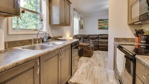 A kitchen with granite countertops, stainless steel appliances, and a leather sofa in the dining area. - Oakland Oasis: Serene Retreat in the Ozarks (Oakland)