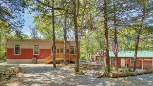 A rustic cabin with a wooden deck, surrounded by trees and a gravel path. - Oakland Oasis: Serene Retreat in the Ozarks (Oakland)