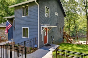 A two-story house with a red door, a small porch, and a dock extending into a lake. - Waterfront Troutman Vacation Rental on Lake Norman (Troutman)