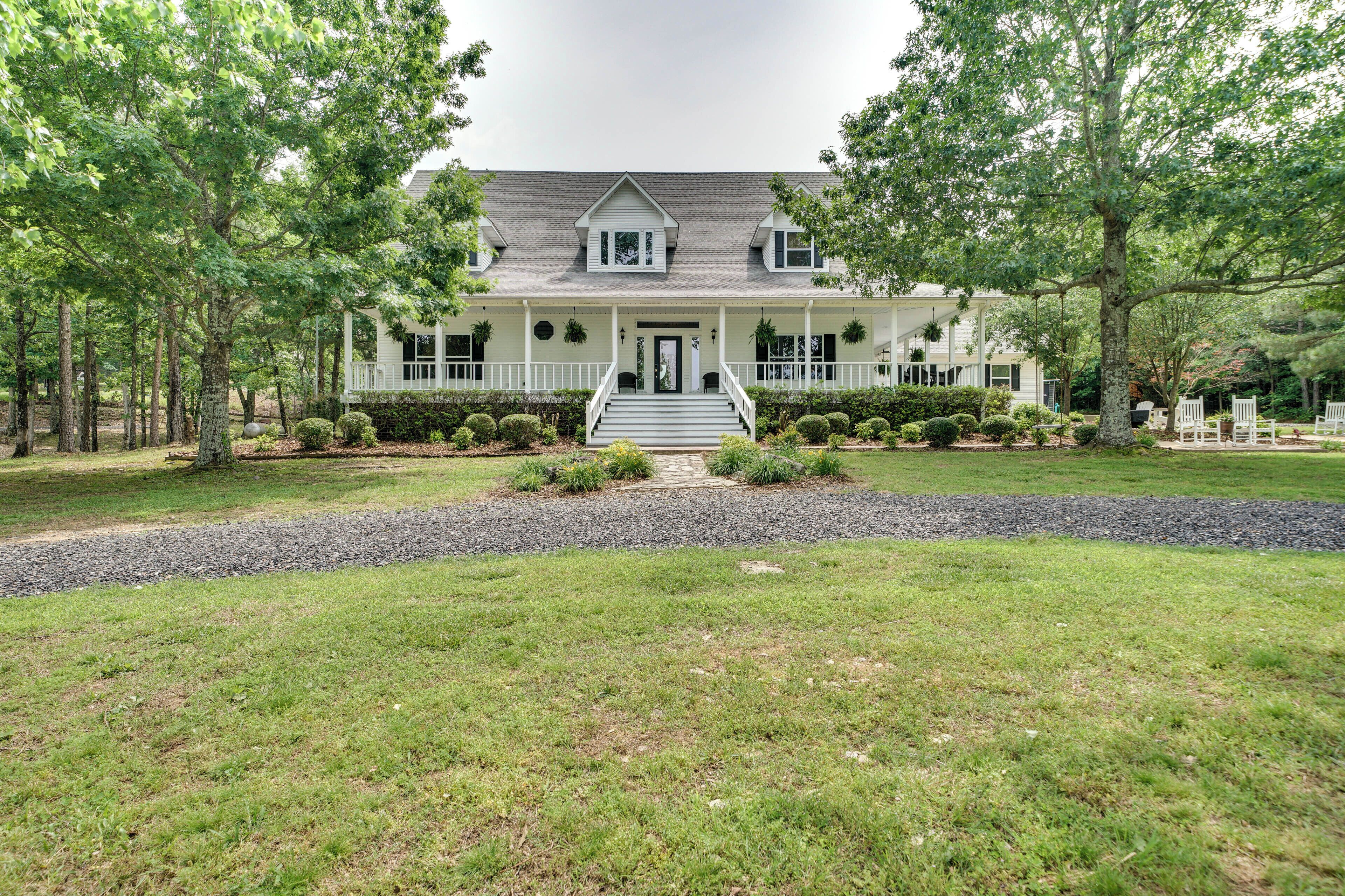 A large, two-story house with a front porch, surrounded by a well-maintained lawn and trees.