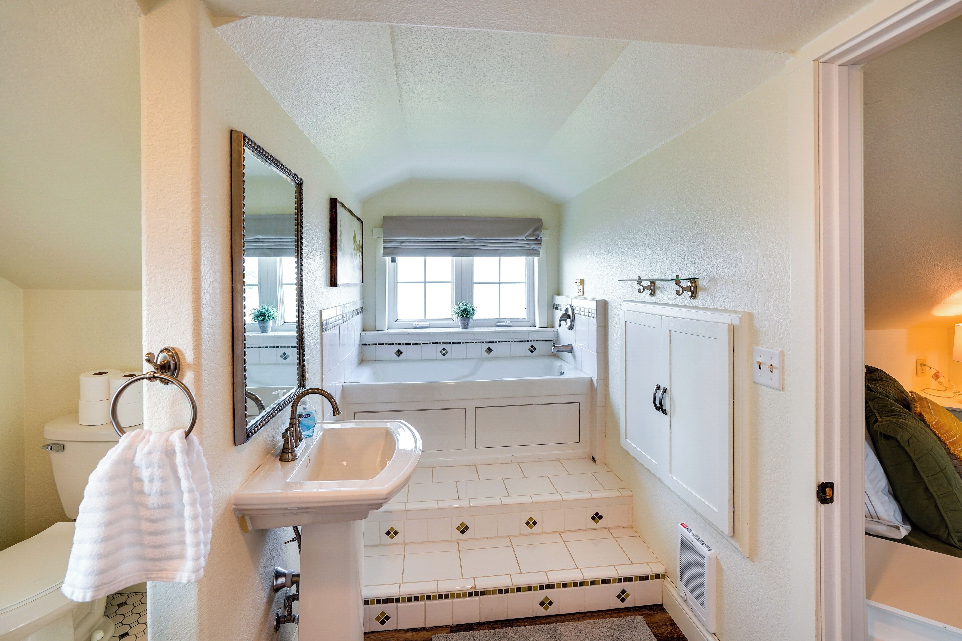 A bathroom with a white sink, a mirror, a toilet, and a bathtub.