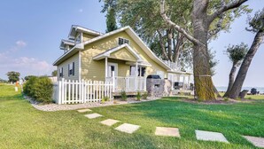 A two-story house with a white picket fence, a stone patio, and a large tree in the yard. - Waterfront Lake Poinsett Retreat w/ Fire Pit! (Castlewood)