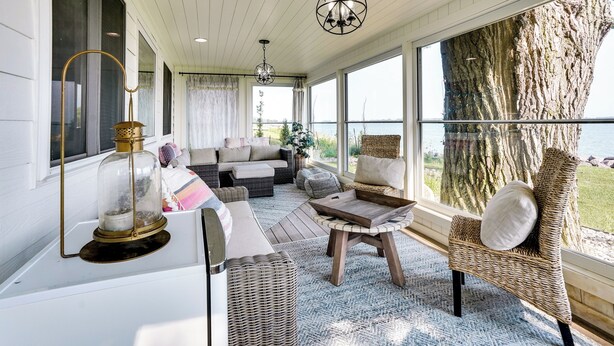 A cozy living room with wicker furniture, a glass table, and a large window overlooking a natural landscape. - Waterfront Lake Poinsett Retreat w/ Fire Pit! (Castlewood)