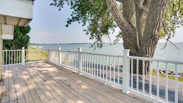 Enjoy a serene view from this deck overlooking the water, surrounded by a large tree for shade.