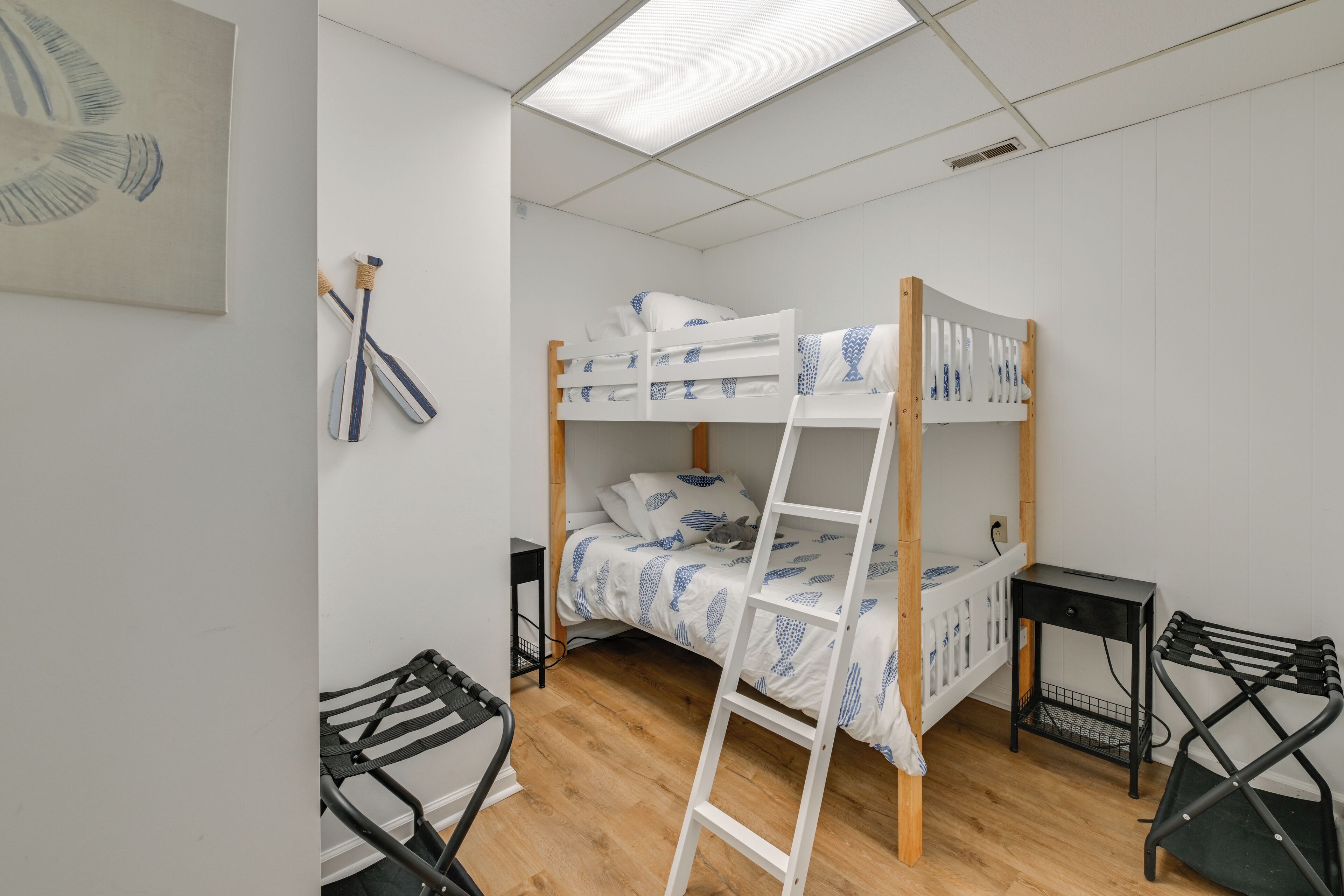 Een slaapkamer met een stapelbed, een houten ladder, een tafeltje en een stoel.