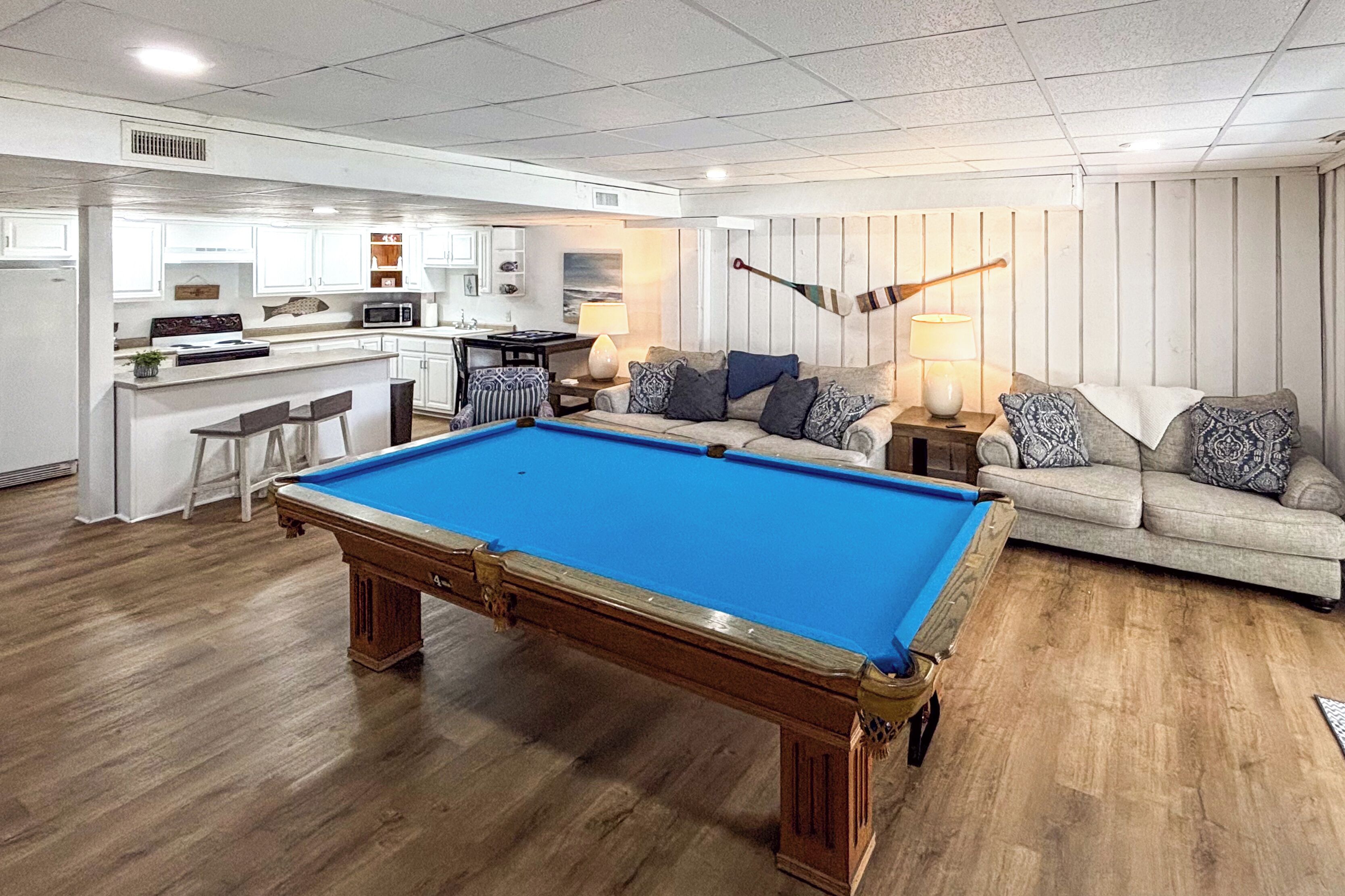 A pool table in a living room with a sofa and a lamp.