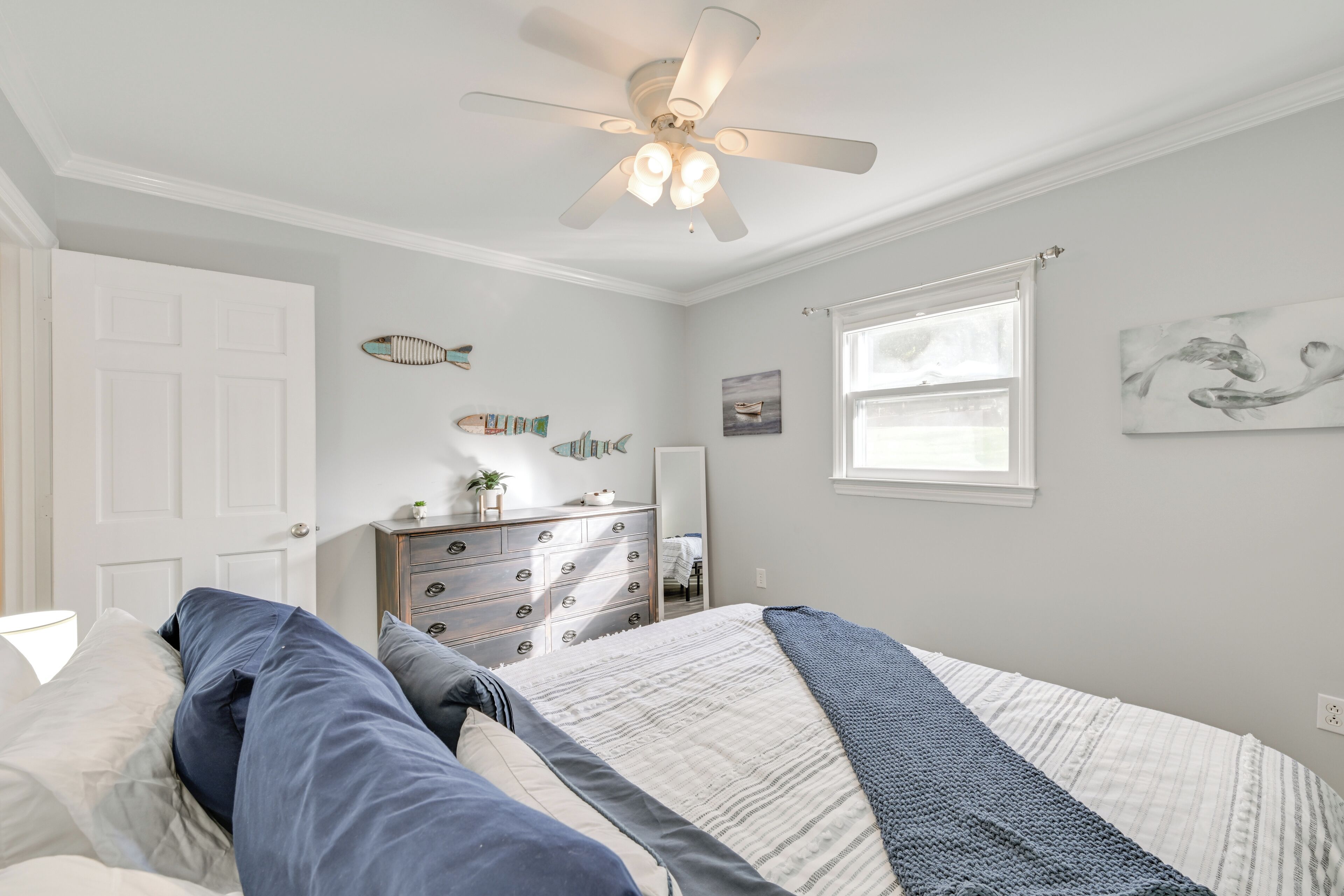 Ein Schlafzimmer mit Bett, Kommode und Deckenventilator.