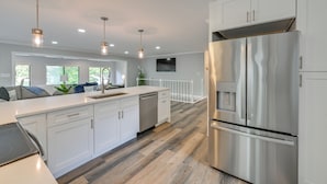 A modern kitchen with white cabinetry, stainless steel appliances, and a wooden floor. - Spacious Lake Norman Retreat w/ Boat Ramp! (Sherrills Ford)