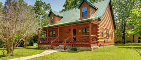 A log cabin with a porch, two chimneys, and a stone foundation.