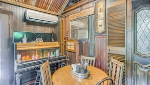 Un interior de estilo antiguo con una mesa de madera, sillas, una caja registradora vintage y objetos decorativos.