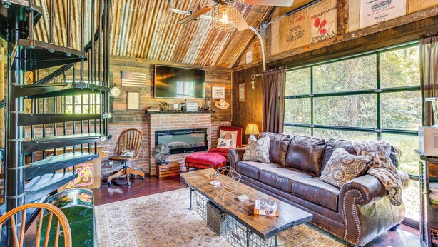Un interior rústico con chimenea, sofá de cuero y escalera de madera.