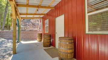 A red building with a stone wall, wooden barrels, and a covered porch.