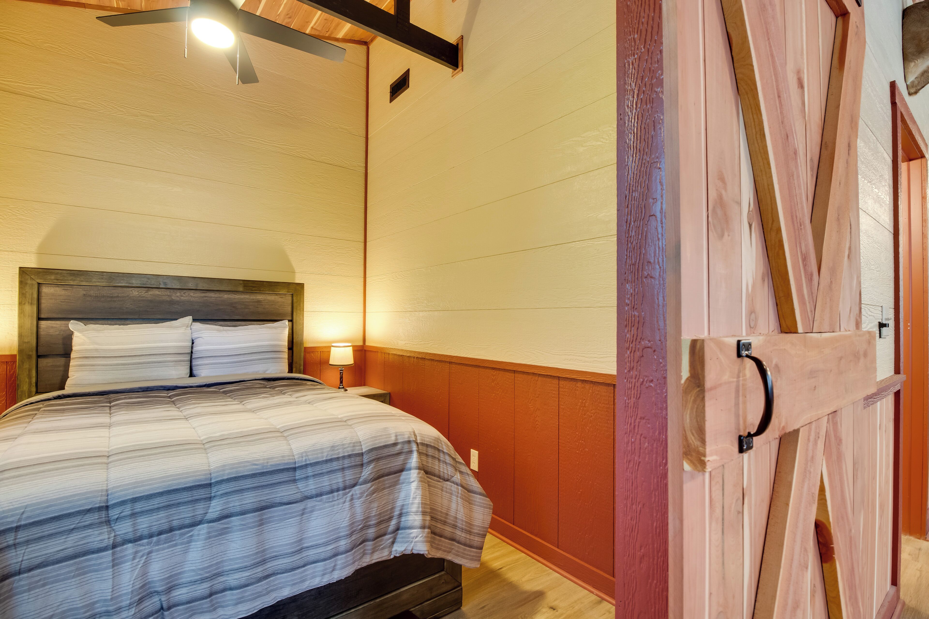 A bedroom with a bed, bedside lamps, a wooden headboard, and a ceiling fan.