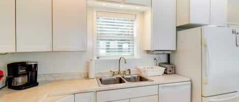 A kitchen with white cabinets, a double sink, a coffee maker, a toaster, and a refrigerator.