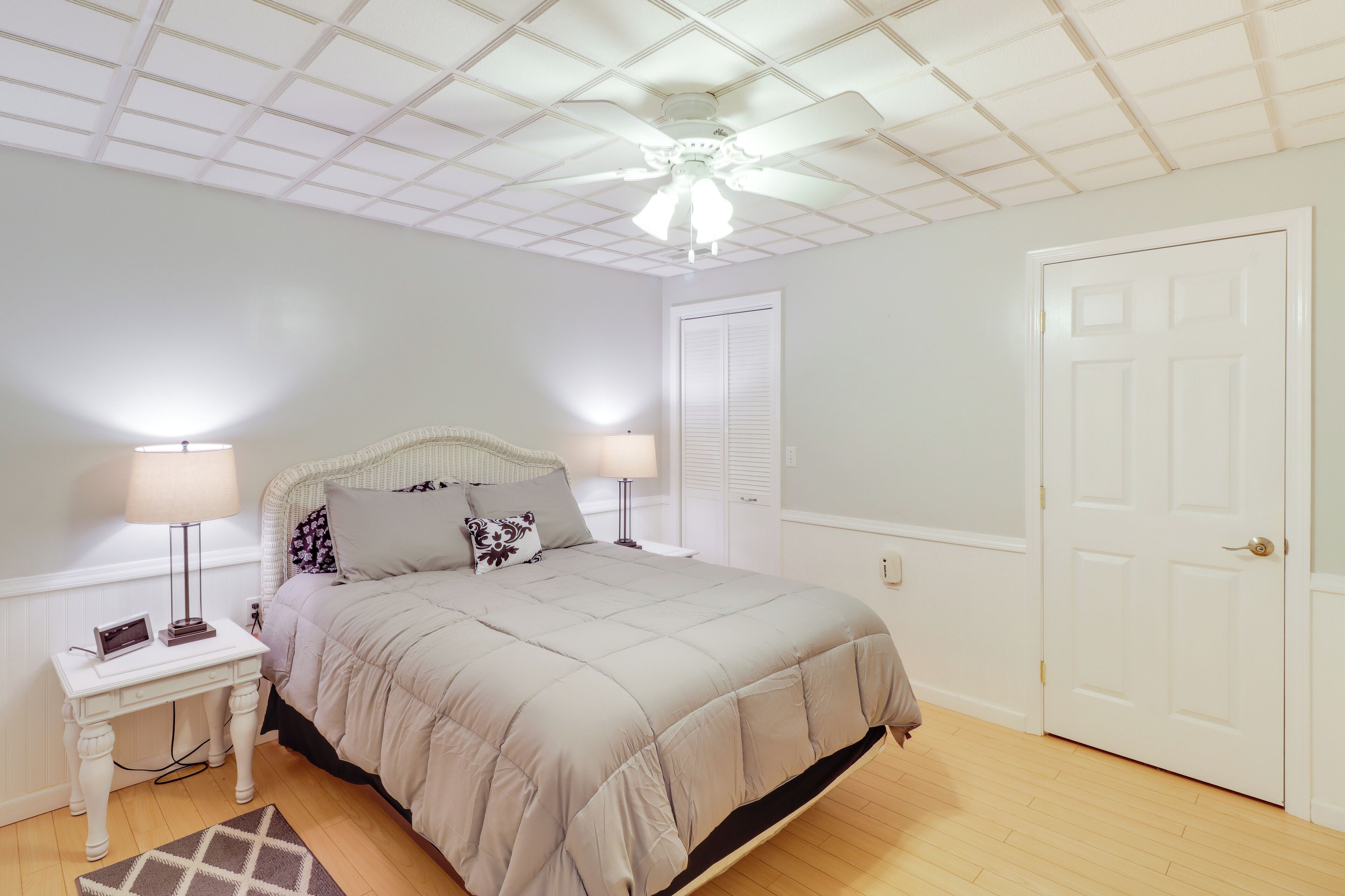 Un dormitorio con cama, mesita de noche, lámpara y ventilador de techo.