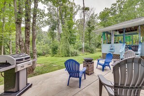 An outdoor patio with a grill, two blue Adirondack chairs, and a small table. - Peaceful Pocono Retreat: Hot Tub & Covered Deck! (Stroudsburg)