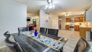 A dining area with a black table, blue floral table runner, and a vase with flowers.
