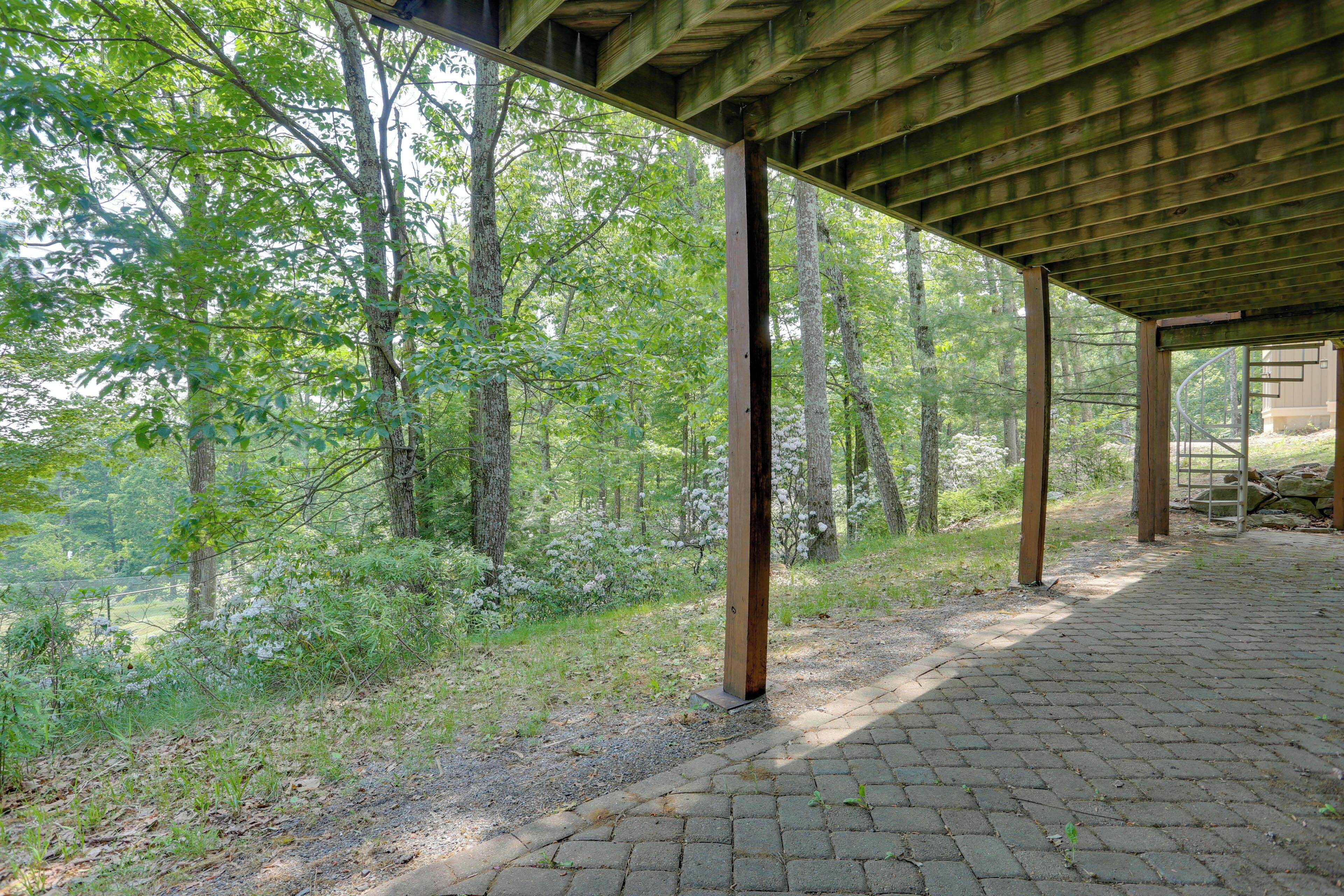 A covered outdoor area with a brick pathway, surrounded by trees and greenery.