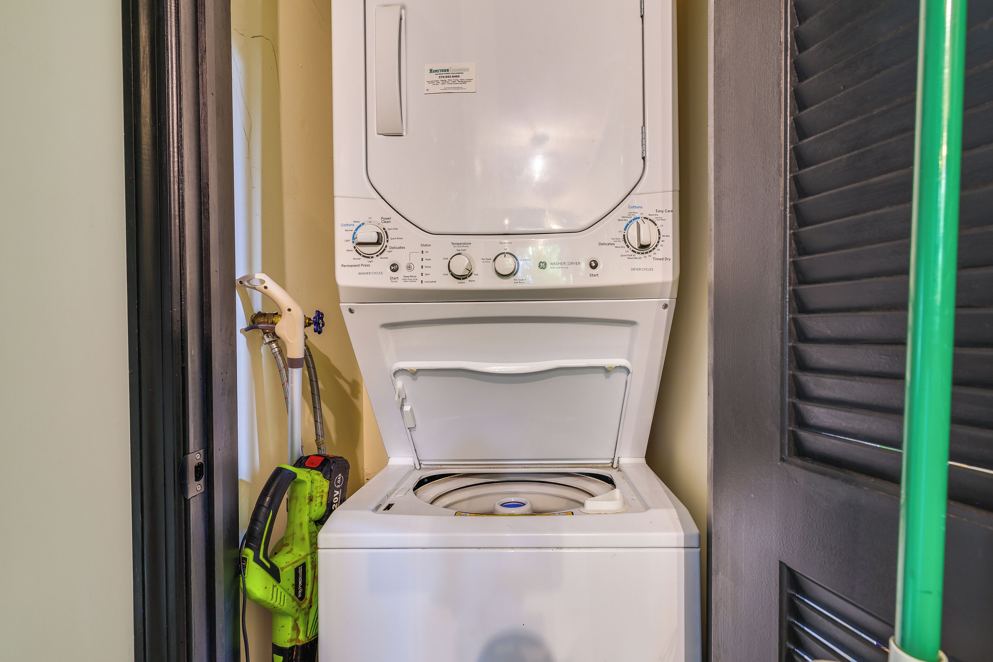 A compact, white front-loading washer and dryer unit with control knobs and a hose attached.