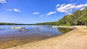 Une plage avec une eau cristalline, des gens qui se baignent et des bateaux.