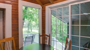 A wooden deck with a table and chairs, large windows, and a view of trees. - Cozy Tennessee Cabin w/ Deck, Grill & Fire Pit! (Tullahoma)
