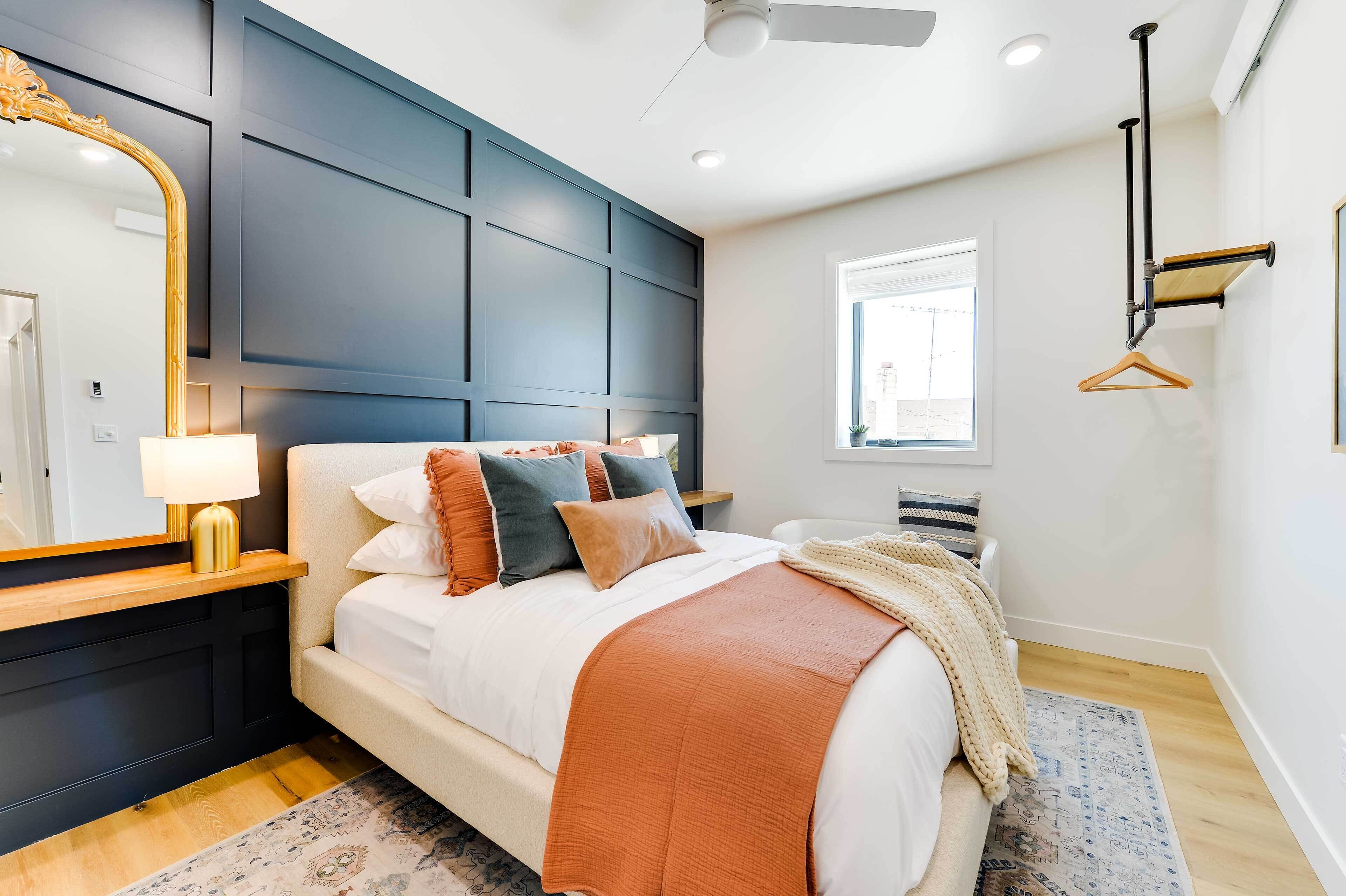 Quarto moderno com uma cama grande, penteadeira, espelho, luminária pendente e janela.