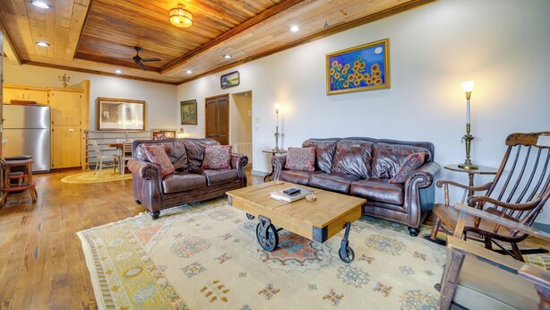 A spacious living room with a wooden ceiling, leather sofas, a coffee table, and a rug.