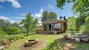A rustic cabin with a wooden deck, a fire pit, and outdoor furniture.