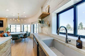 A modern kitchen with a large island, a built-in oven, and a window with a view of the city.