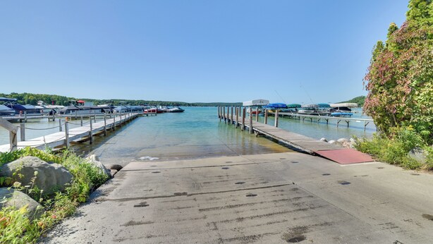 A marina with docks and boats, a clear sky, and a calm water body. - Walloon Lake Getaway w/ Fire Pit - Walk to Water! (Walloon Lake)