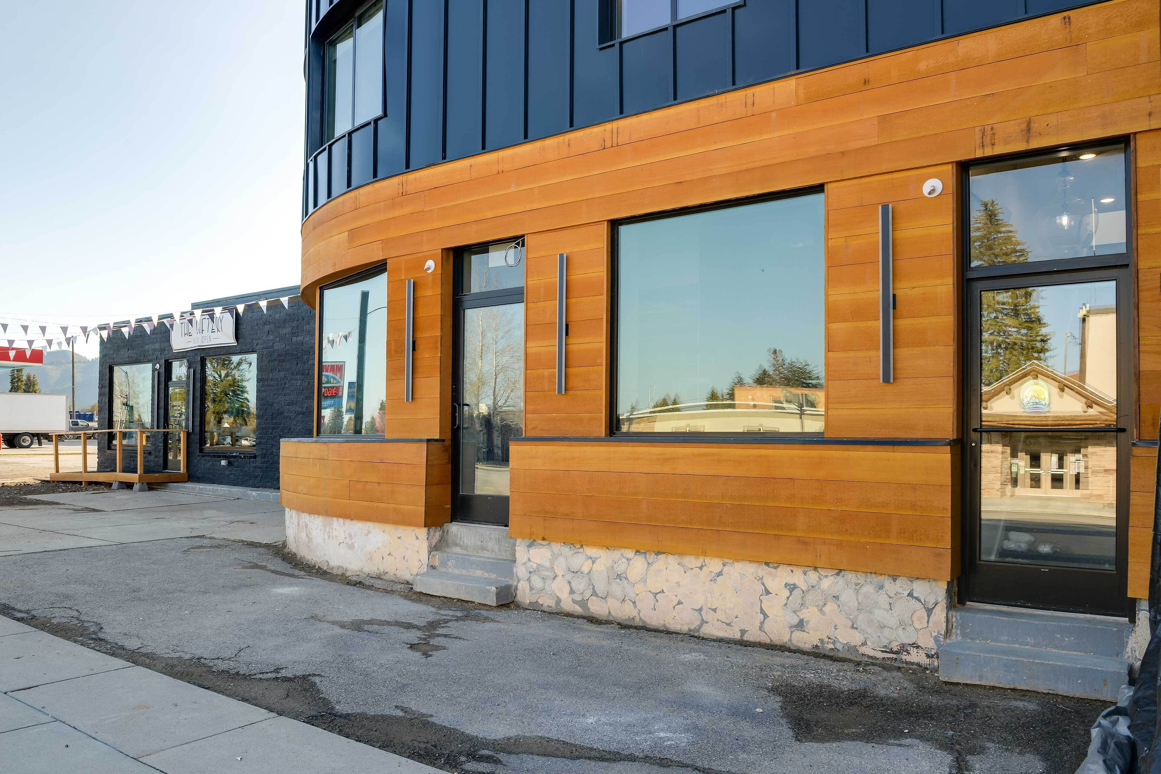 A modern building with large windows and a stone base.