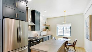 A modern kitchen with stainless steel appliances, dark cabinetry, and a central island with seating. - The Lofts on 89 Condo Near Bridger Nat'l Forest! (Afton)