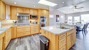 A modern kitchen with wooden cabinets, stainless steel appliances, and a large island with a sink.